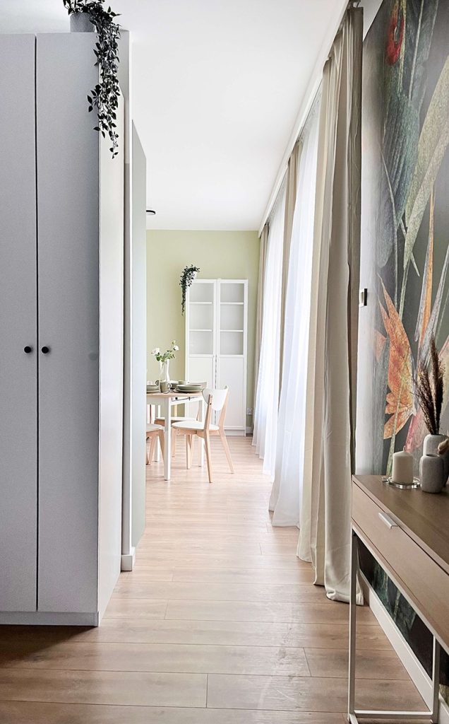 Jasny korytarz z drewnianą podłogą i widokiem na część dzienną z jadalnią - mieszkanie 1-pokojowe na wynajem - Łódź, dzielnica Bałuty