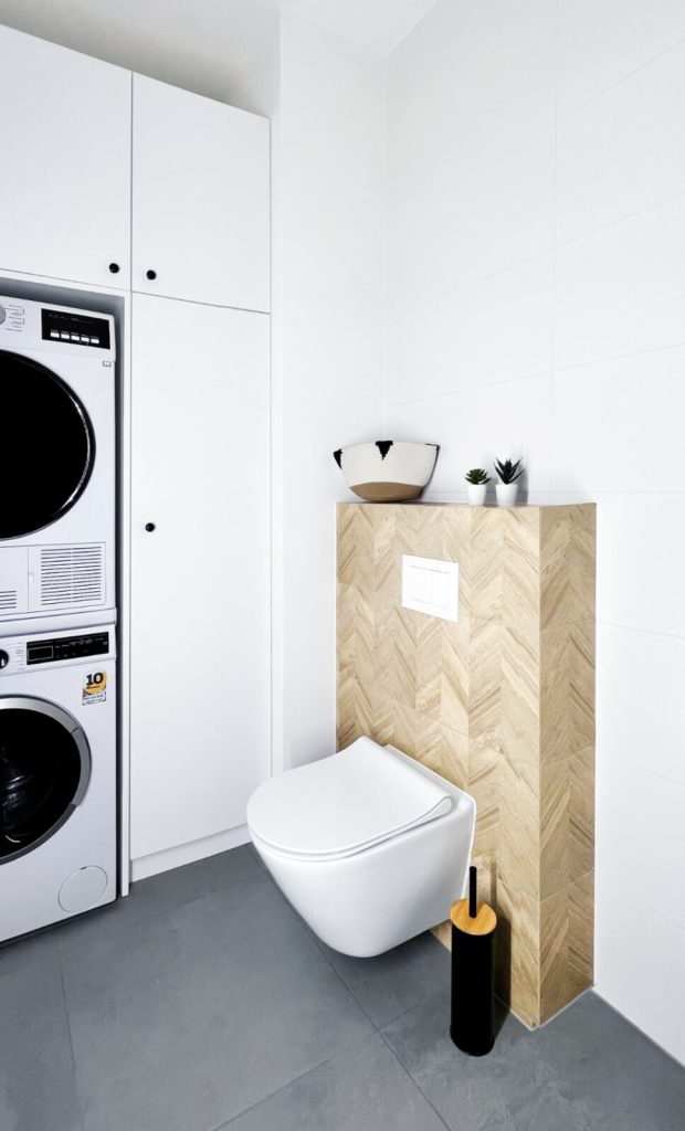 Nowoczesna łazienka z zabudowaną pralką i suszarką, białą ceramiką i ciemną podłogą - kawalerka na wynajem Łódź Pomorska 107a