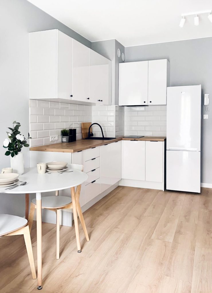 Widok na biały aneks kuchenny, duża biała lodówka, zmywarka w zabudowie - mieszkanie na wynajem - Łódź Pomorska 107a