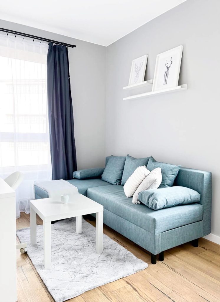 Jasny salon z błękitną rozkładaną sofą narożną, stolikiem kawowym - mieszkanie na wynajem Łódź Śródmieście