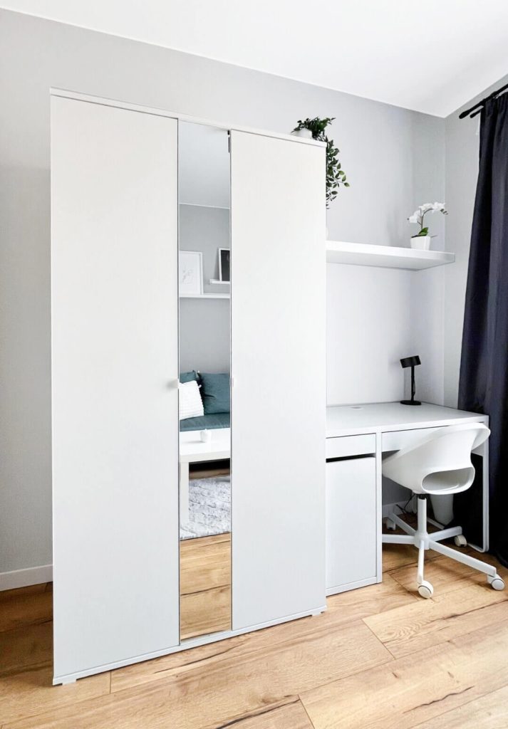 Pokój z białym biurkiem z czarną lampką i białym fotelem na kółkach i białą szafą, jasne szare ściany - mieszkanie na wynajem Łódź Śródmieście